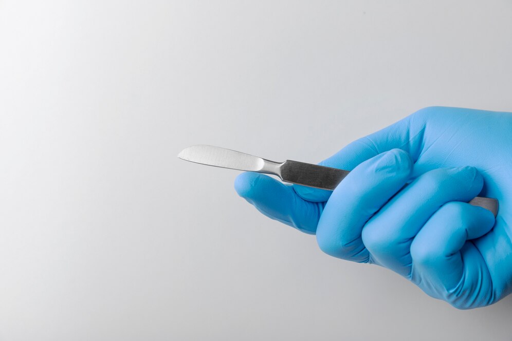 hand-with-rubber-glove-holding-medical-scalpel