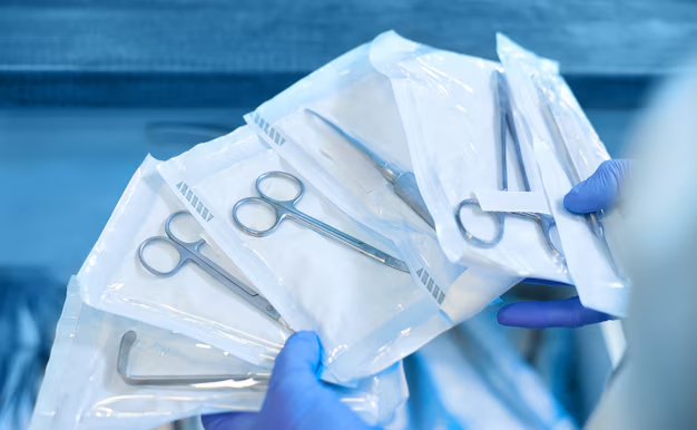 Livingstone dental sterilisation pouches with tools held by a professional in blue nitrile gloves.