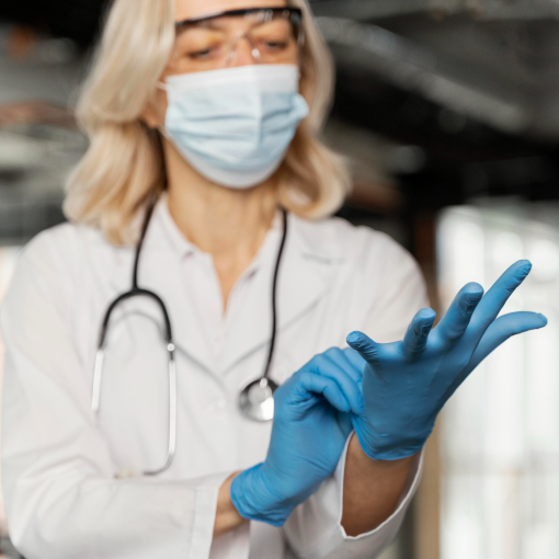 Doctor with medical mask putting on medical gloves