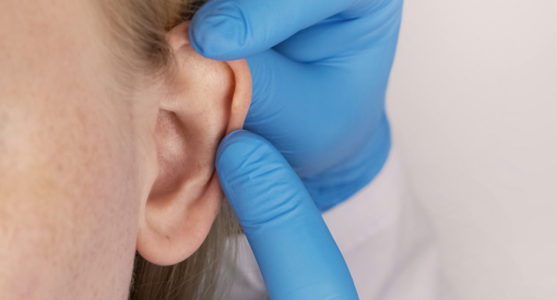 hand with gloves touching patient's ear