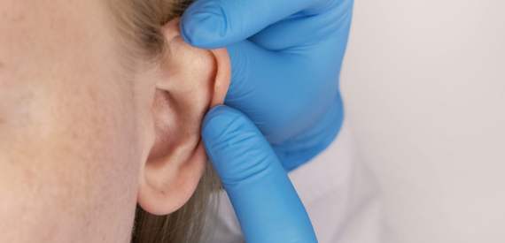 hand with gloves touching patient's ear