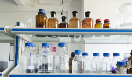 Laboratory reagent bottles with screw caps and glass stopper bottles displayed on a laboratory shelf