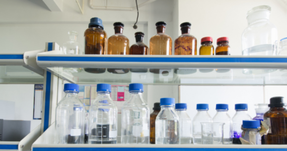 Laboratory reagent bottles with screw caps and glass stopper bottles displayed on a laboratory shelf