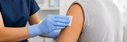 Healthcare worker using an alcohol swab to disinfect skin before an injection.